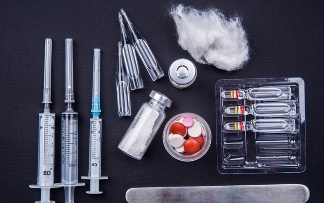 grouping of steroid drugs in syringes and tablets black background