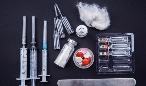 grouping of steroid drugs in syringes and tablets black background